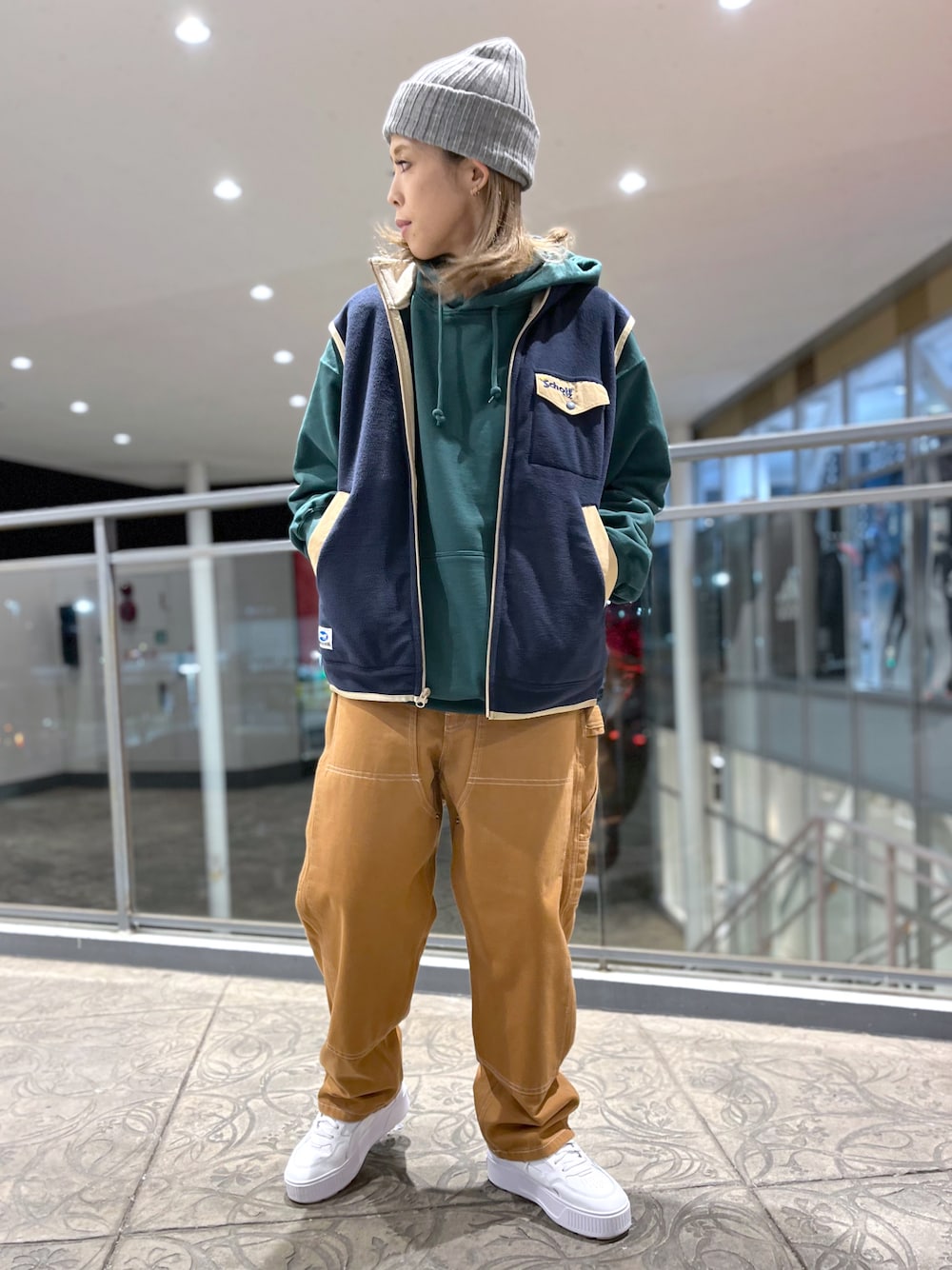 ブラック系のパーカー、ブルー系のベスト、ブラウン系のその他パンツを着用したレディースの冬コーディネートの1枚目の写真