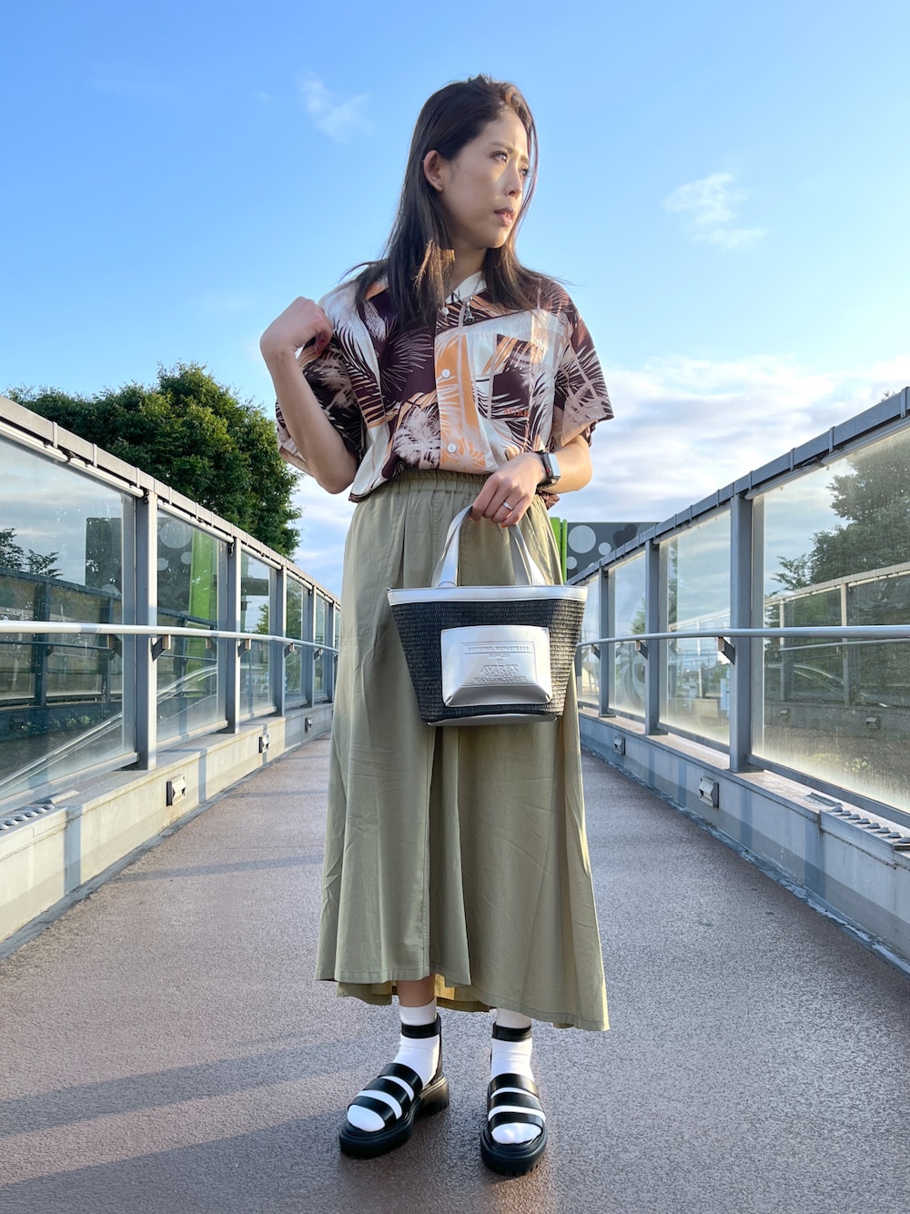 ブラック系のサンダル、グリーン系のスカート、シルバー系のトートバッグを着用したレディースの夏コーディネートの1枚目の写真