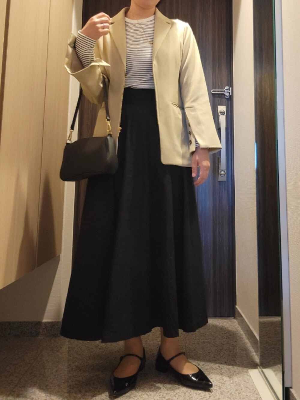 ベージュ系のテーラードジャケット、ブラック系のバッグ、ブラック系のスカートを着用したレディースの春コーディネートの1枚目の写真