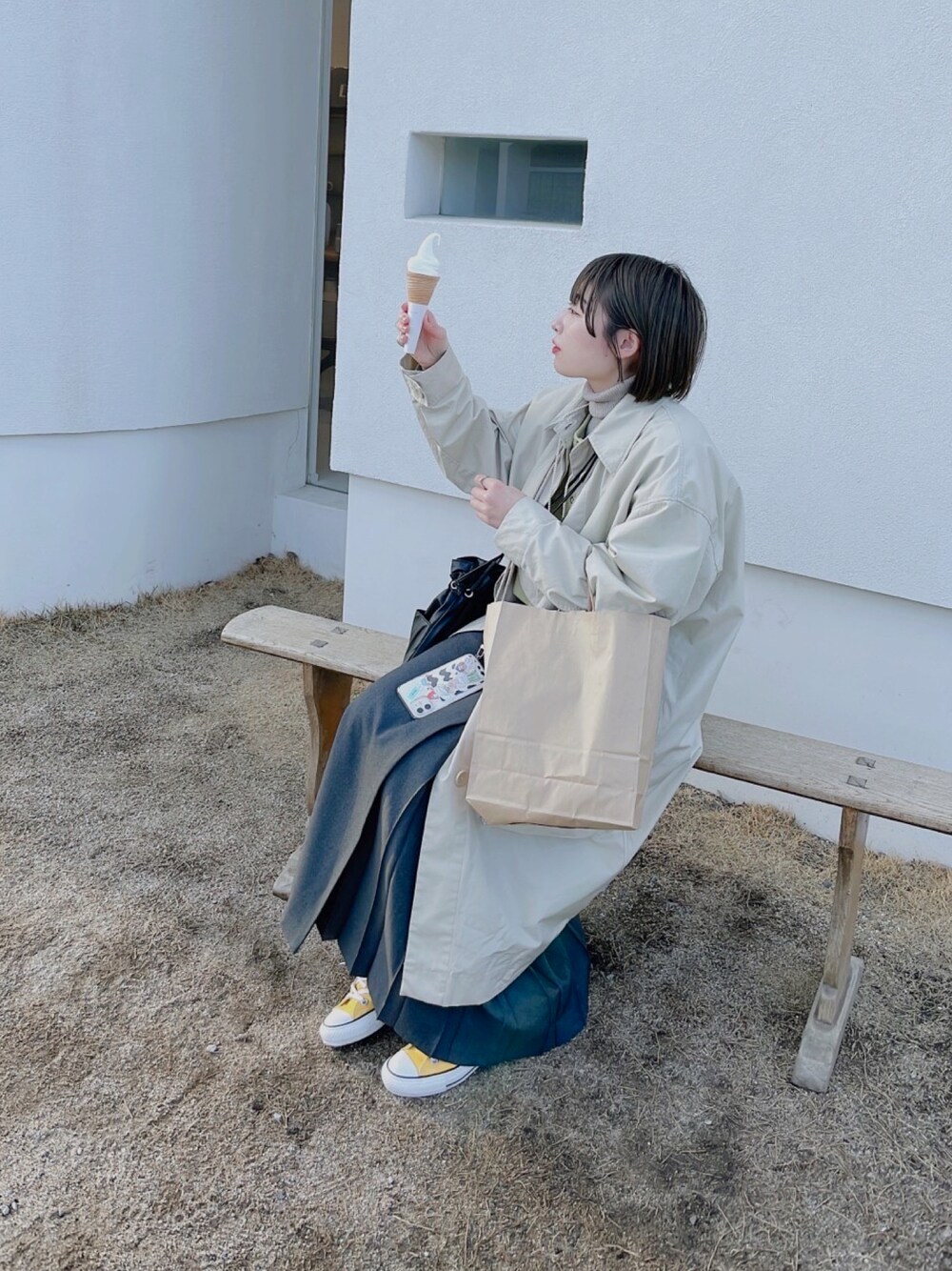 イエロー系のスニーカー、グレー系のスカート、ブラック系のショルダーバッグを着用したレディースの冬コーディネートの1枚目の写真