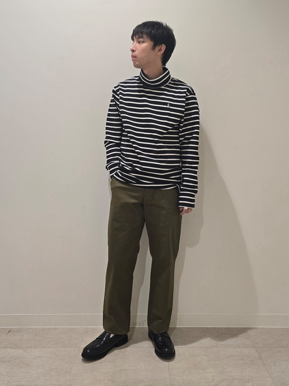 グリーン系のスラックス、ブラック系のTシャツ/カットソー、ブラック系のドレスシューズを着用したメンズの秋コーディネートの1枚目の写真