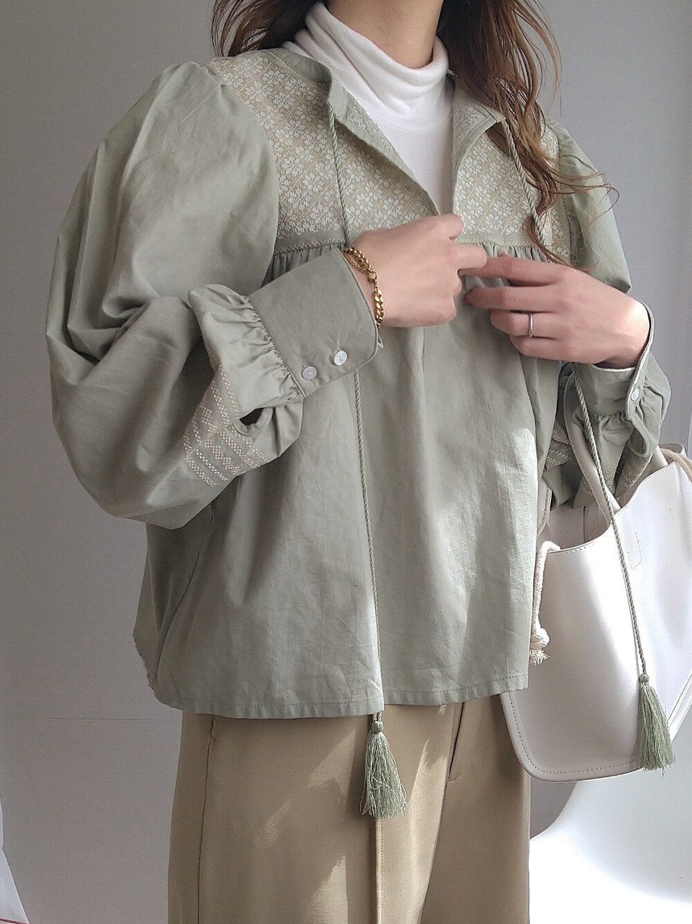 グリーン系のシャツ/ブラウス、イエロー系のスラックス、ベージュ系のサンダルを着用したレディースの春コーディネートの2枚目の写真