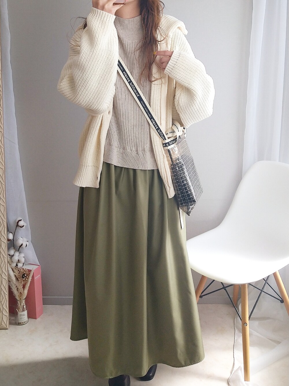 グリーン系のワンピース、ホワイト系のカーディガン/ボレロ、ブラック系のショルダーバッグを着用したレディースの春コーディネートの2枚目の写真