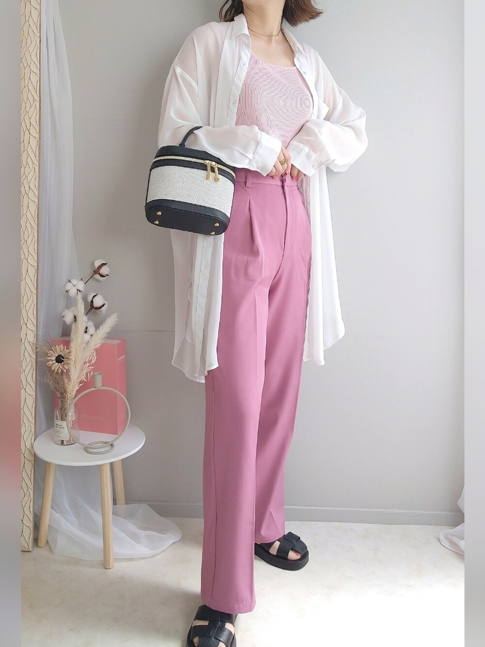 ピンク系のトップス、ピンク系のスラックス、ブラック系のサンダルを着用したレディースの春コーディネートの1枚目の写真