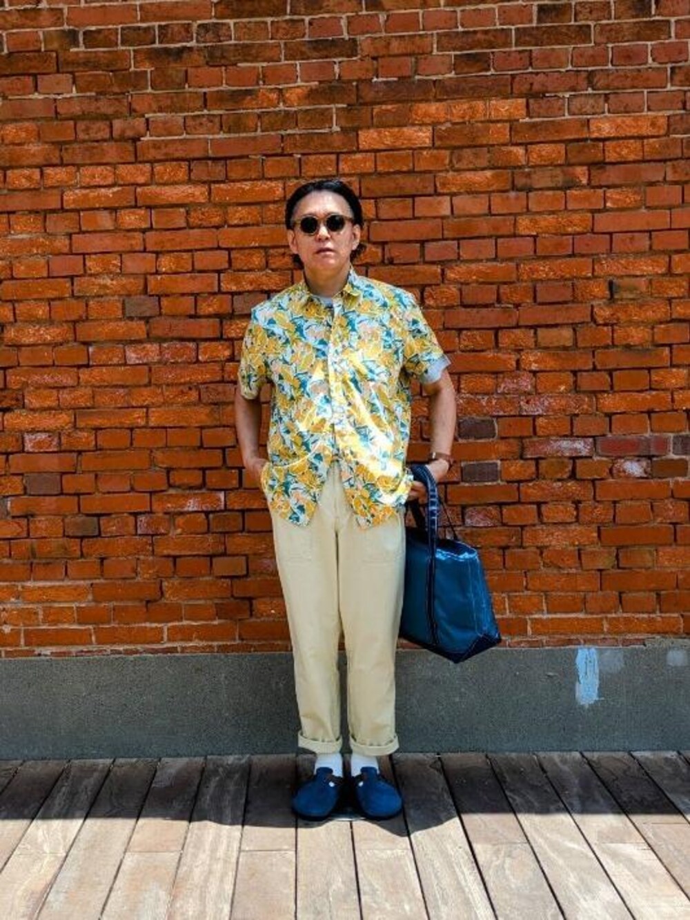 ブルー系のトートバッグ、グレー系のTシャツ/カットソーを着用したメンズの春コーディネートの1枚目の写真