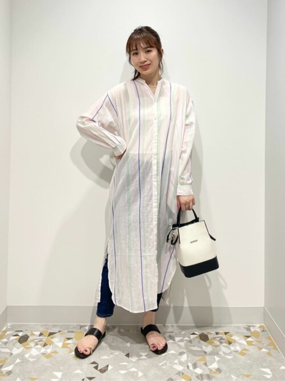 ピンク系のワンピース、ブルー系のデニムパンツ、ブラック系のショルダーバッグを着用したレディースの春コーディネートの1枚目の写真