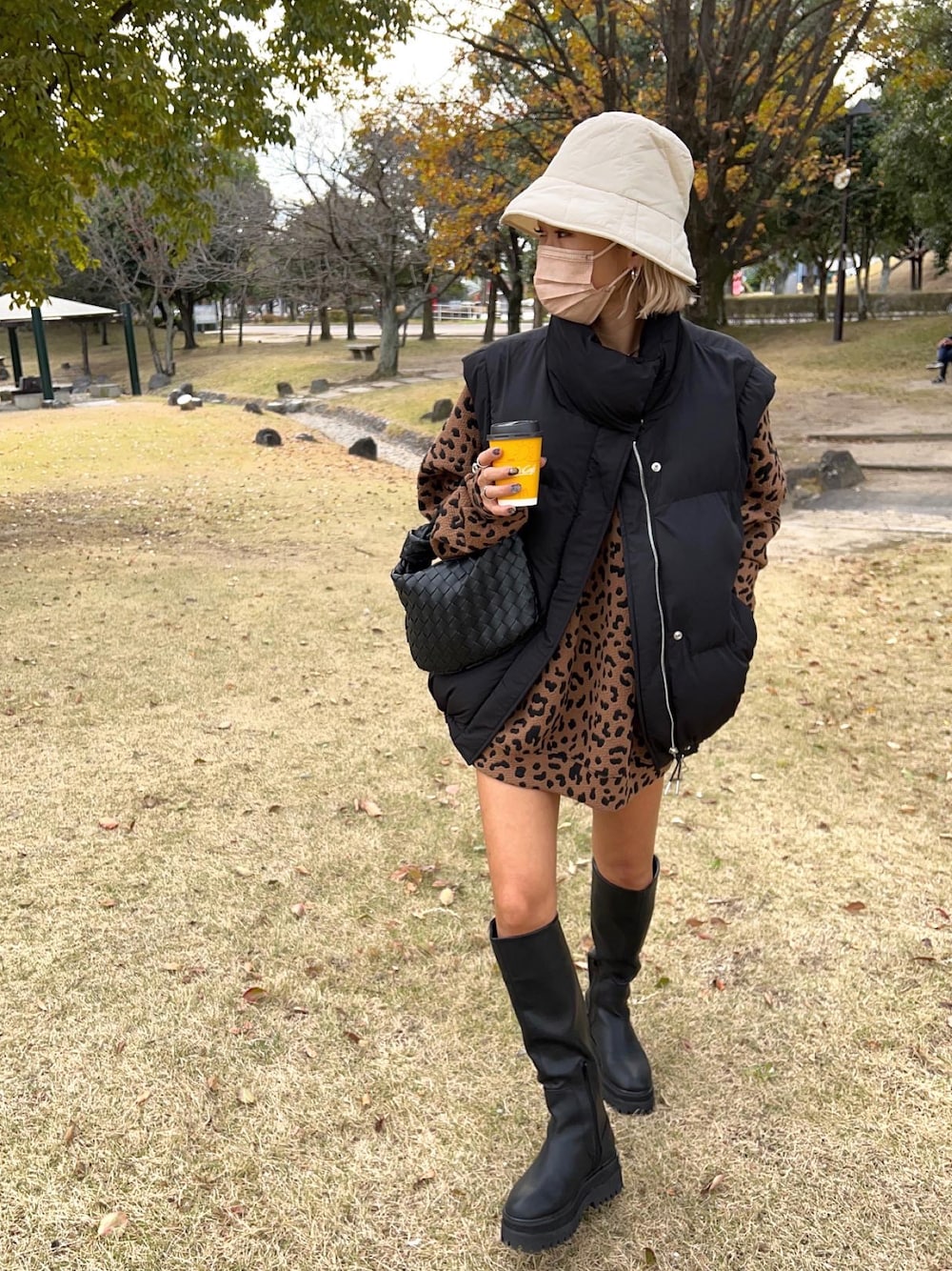 ブラック系のブーツ、ブラック系のハンドバッグ、ブラック系のベストを着用したレディースの冬コーディネートの1枚目の写真