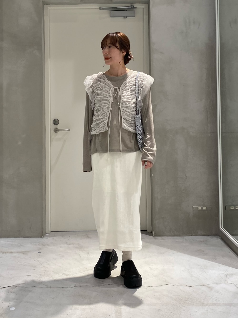 ホワイト系のベスト、シルバー系のトートバッグ、ベージュ系のTシャツ/カットソーを着用したレディースの春コーディネートの1枚目の写真