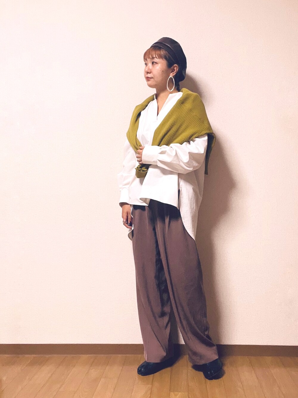 イエロー系のカーディガン/ボレロ、ホワイト系のシャツ/ブラウス、ブラウン系のパンツを着用したレディースの秋コーディネートの1枚目の写真