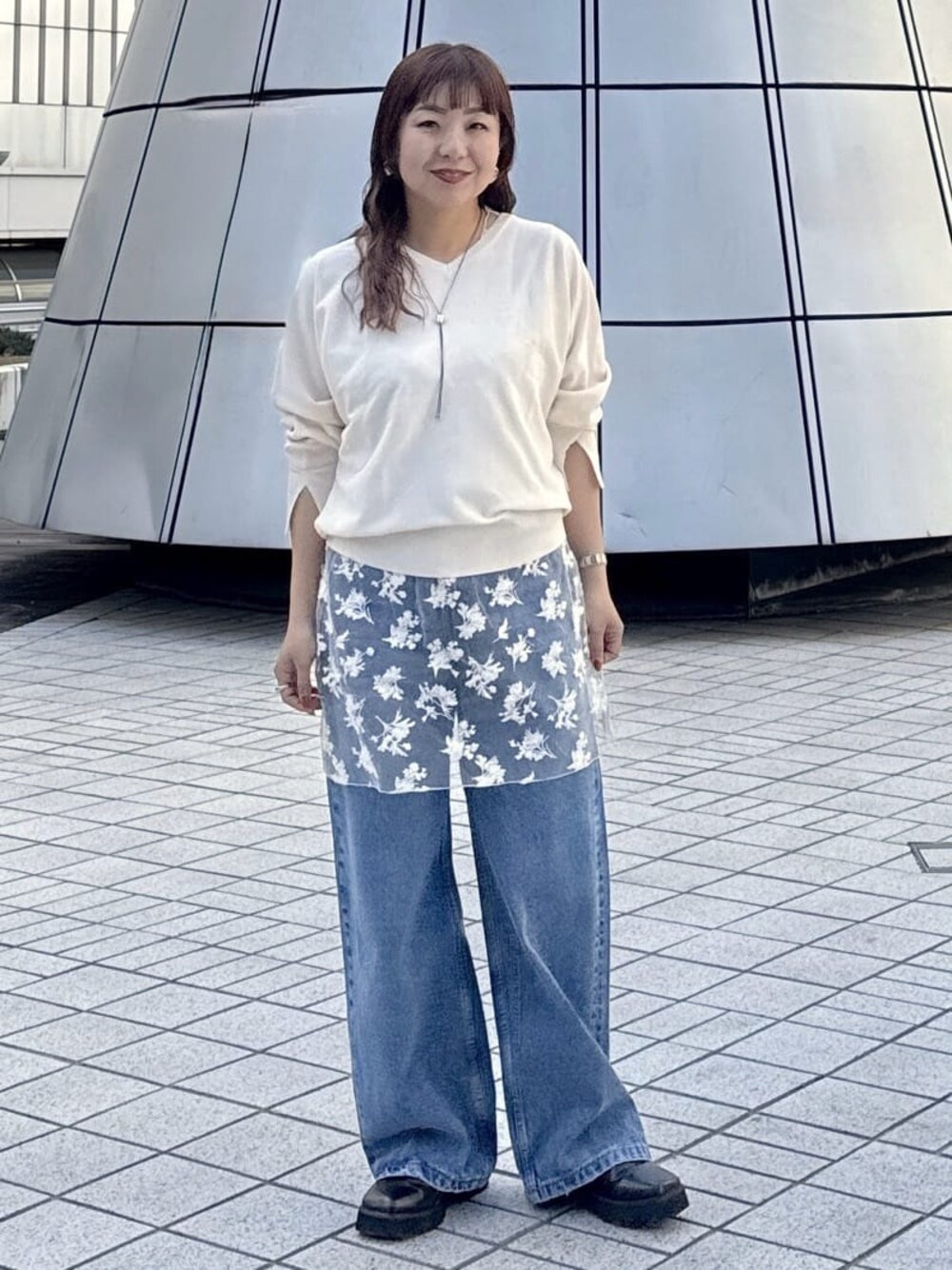ホワイト系のニット/セーター、ホワイト系のシャツ/ブラウス、ブルー系のデニムパンツを着用したレディースの春コーディネートの1枚目の写真