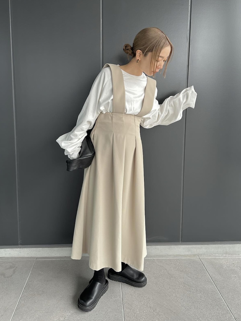 ベージュ系のスカート、ホワイト系のTシャツ/カットソー、ブラック系のスリッポンを着用したレディースの冬コーディネートの1枚目の写真