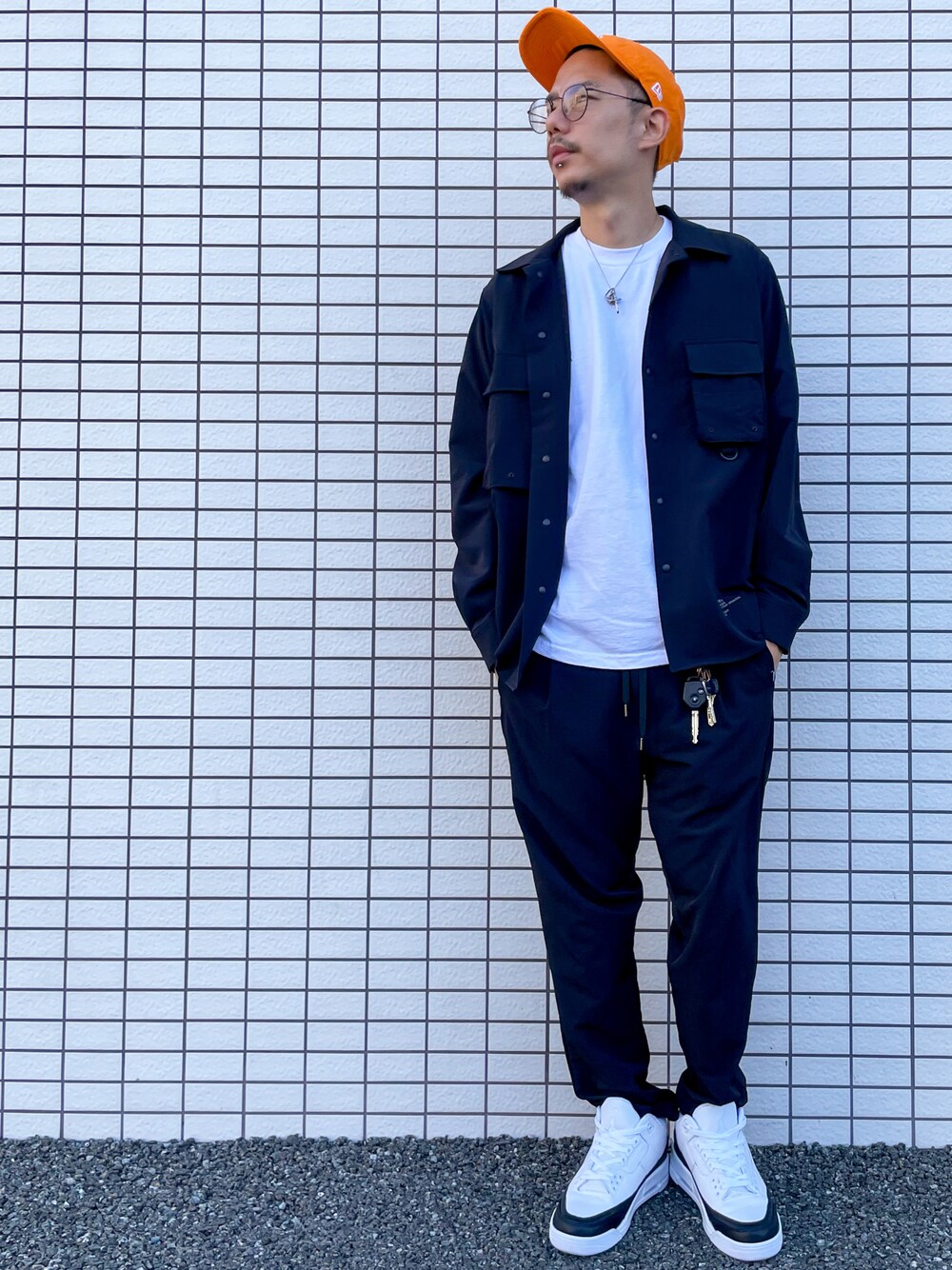 ホワイト系のスニーカー、ブラック系のスラックス、ホワイト系のTシャツ/カットソーを着用したメンズの秋コーディネートの1枚目の写真