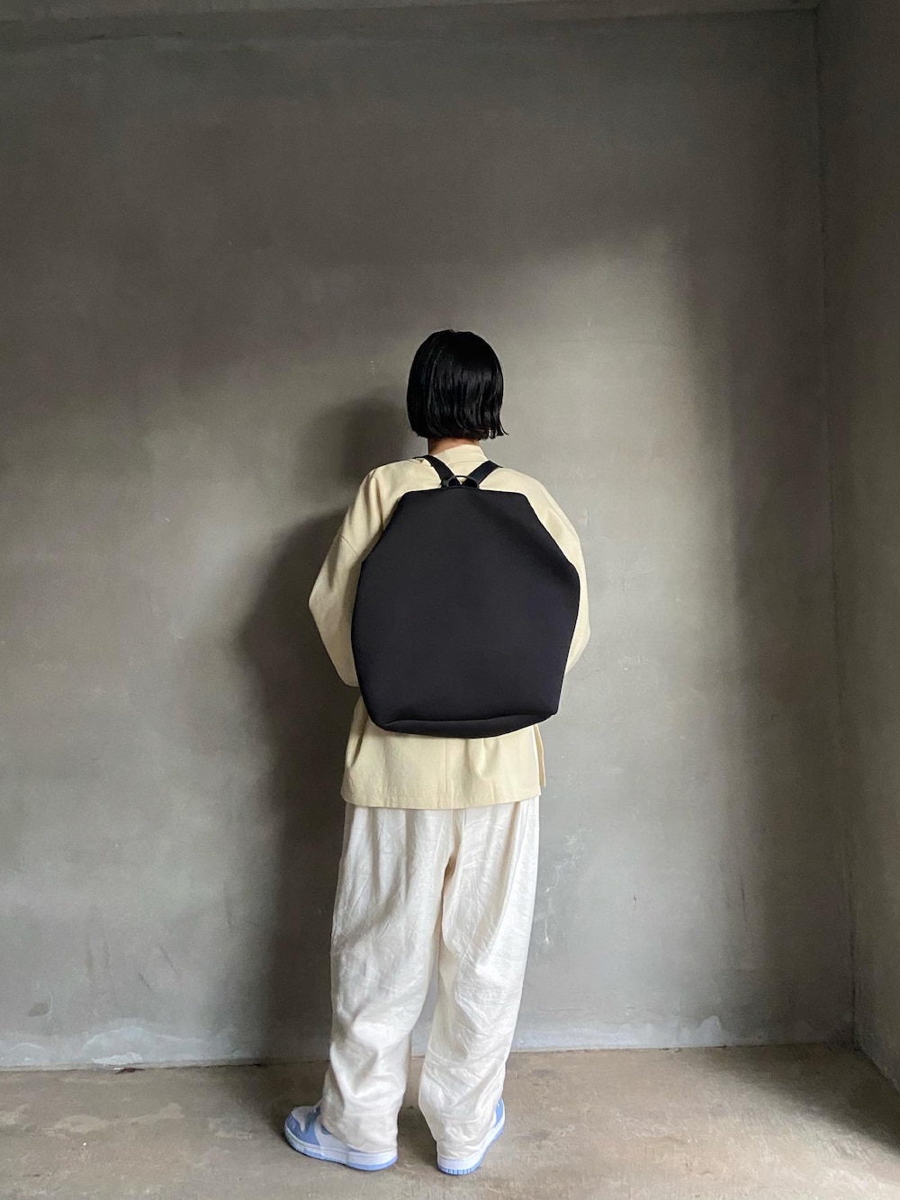 ブラック系のバックパック/リュック、イエロー系のテーラードジャケット、ホワイト系のスニーカーを着用したレディースの夏コーディネートの1枚目の写真