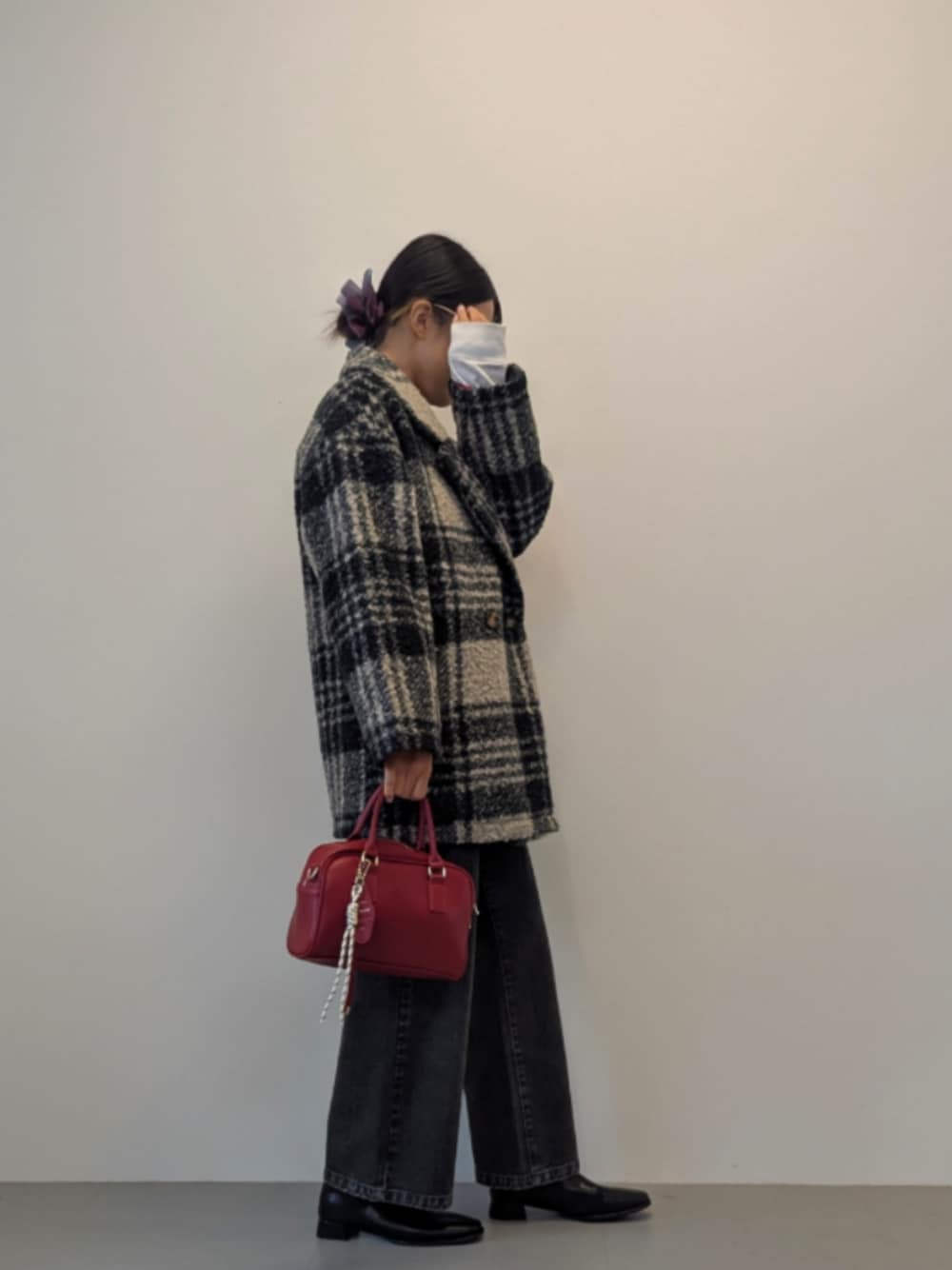 ブラック系のデニムパンツ、レッド系のハンドバッグ、ブラック系のブーツを着用したレディースの秋コーディネートの1枚目の写真