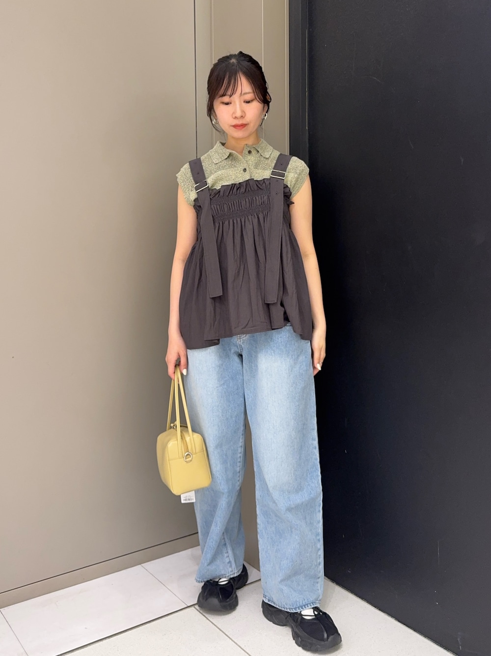 ブルー系のデニムパンツ、ブラック系のスニーカー、ベージュ系のショルダーバッグを着用したレディースの春コーディネートの1枚目の写真