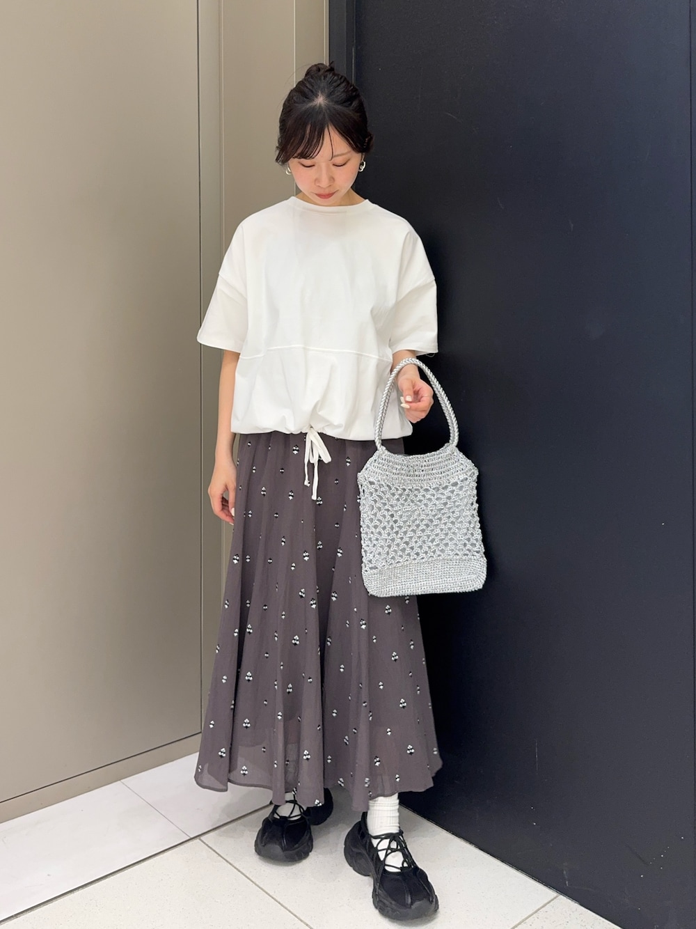 ホワイト系のTシャツ/カットソー、シルバー系のトートバッグ、グレー系のスカートを着用したレディースの春コーディネートの1枚目の写真