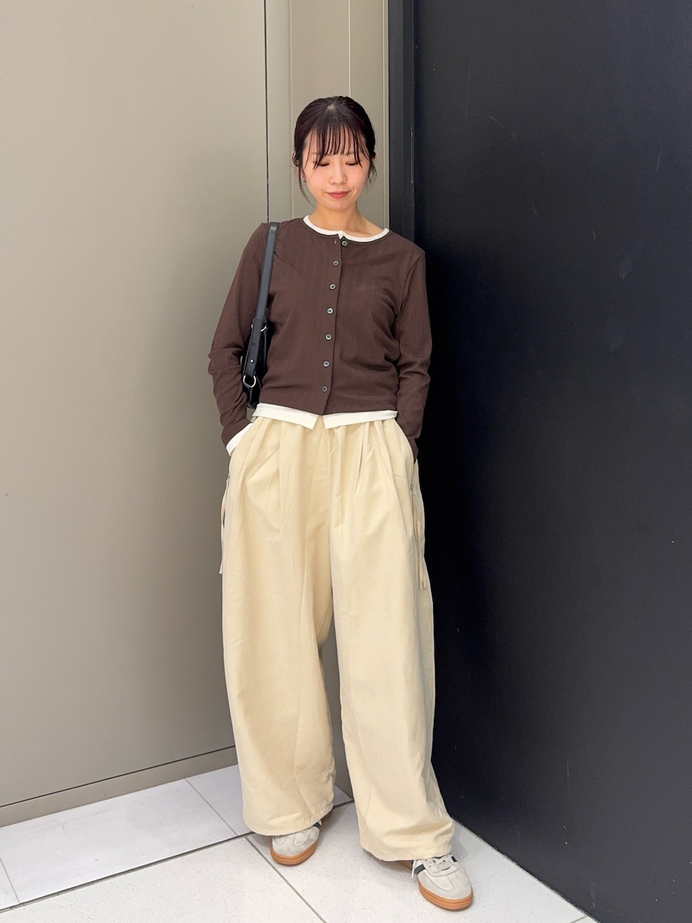 ベージュ系のその他パンツ、ホワイト系のスニーカー、ブラック系のショルダーバッグを着用したレディースの秋コーディネートの1枚目の写真