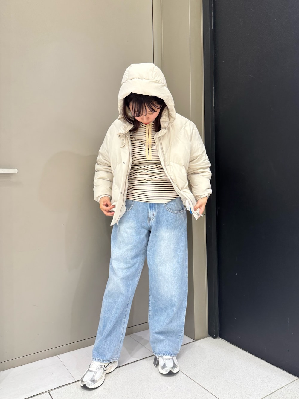 ホワイト系のダウンジャケット/コート、ブルー系のデニムパンツ、ホワイト系のスニーカーを着用したレディースの秋コーディネートの1枚目の写真