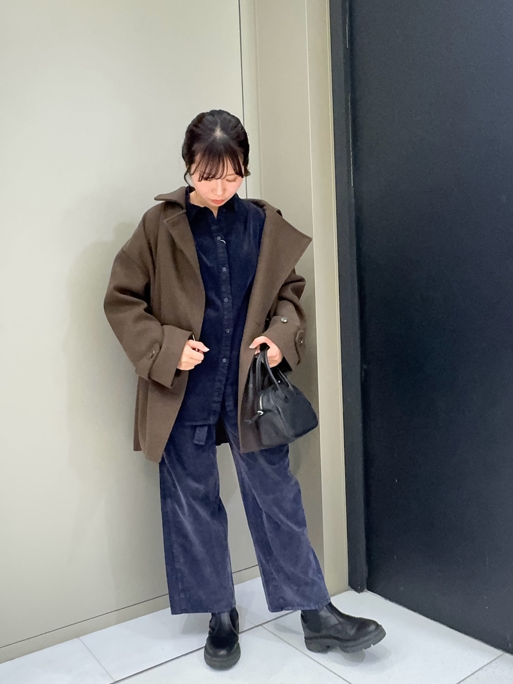 ブラウン系のその他アウター、ブラック系のハンドバッグ、ブルー系のその他パンツを着用したレディースの冬コーディネートの1枚目の写真