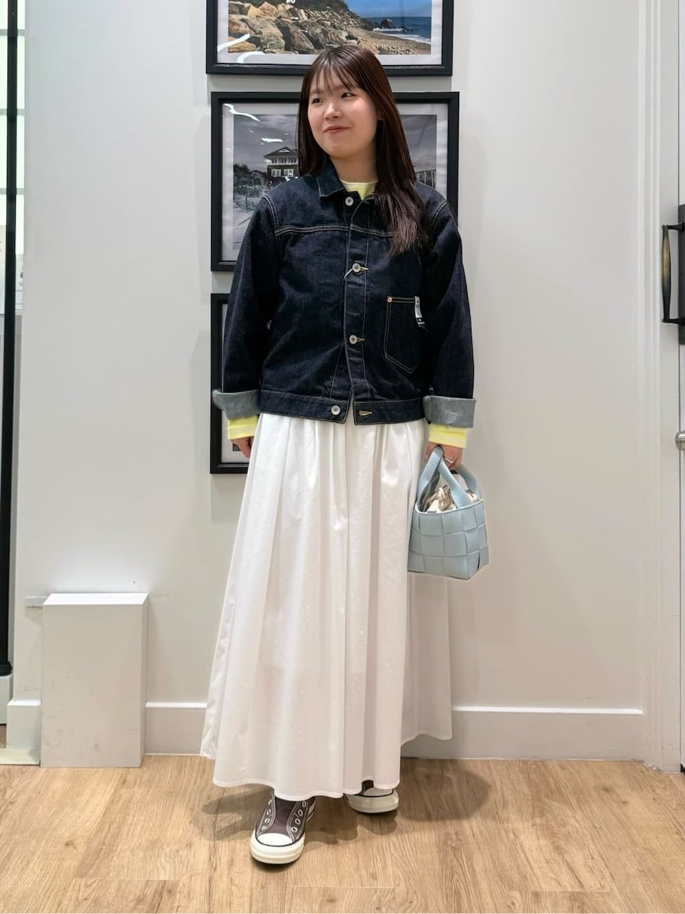 ブルー系のデニムジャケット、ホワイト系のスカート、ブルー系のトートバッグを着用したレディースの冬コーディネートの1枚目の写真