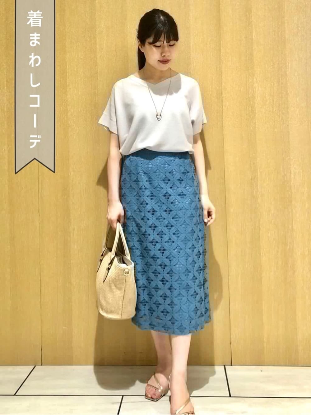 グレー系のニット/セーター、ブルー系のスカートを着用したレディースの夏コーディネートの1枚目の写真