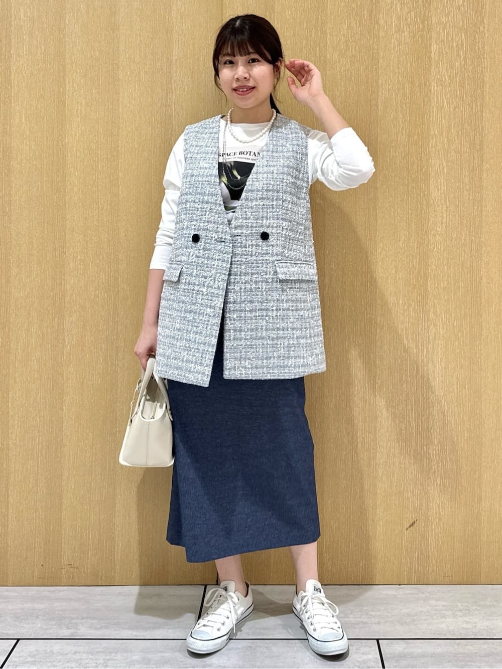 ベージュ系のトートバッグ、ブルー系のスカート、ホワイト系のTシャツ/カットソーを着用したレディースの冬コーディネートの1枚目の写真
