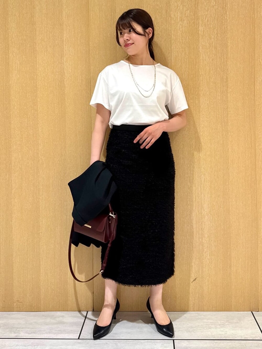 ブラック系のベスト、ホワイト系のTシャツ/カットソー、ブラウン系のスカートを着用したレディースの夏コーディネートの1枚目の写真