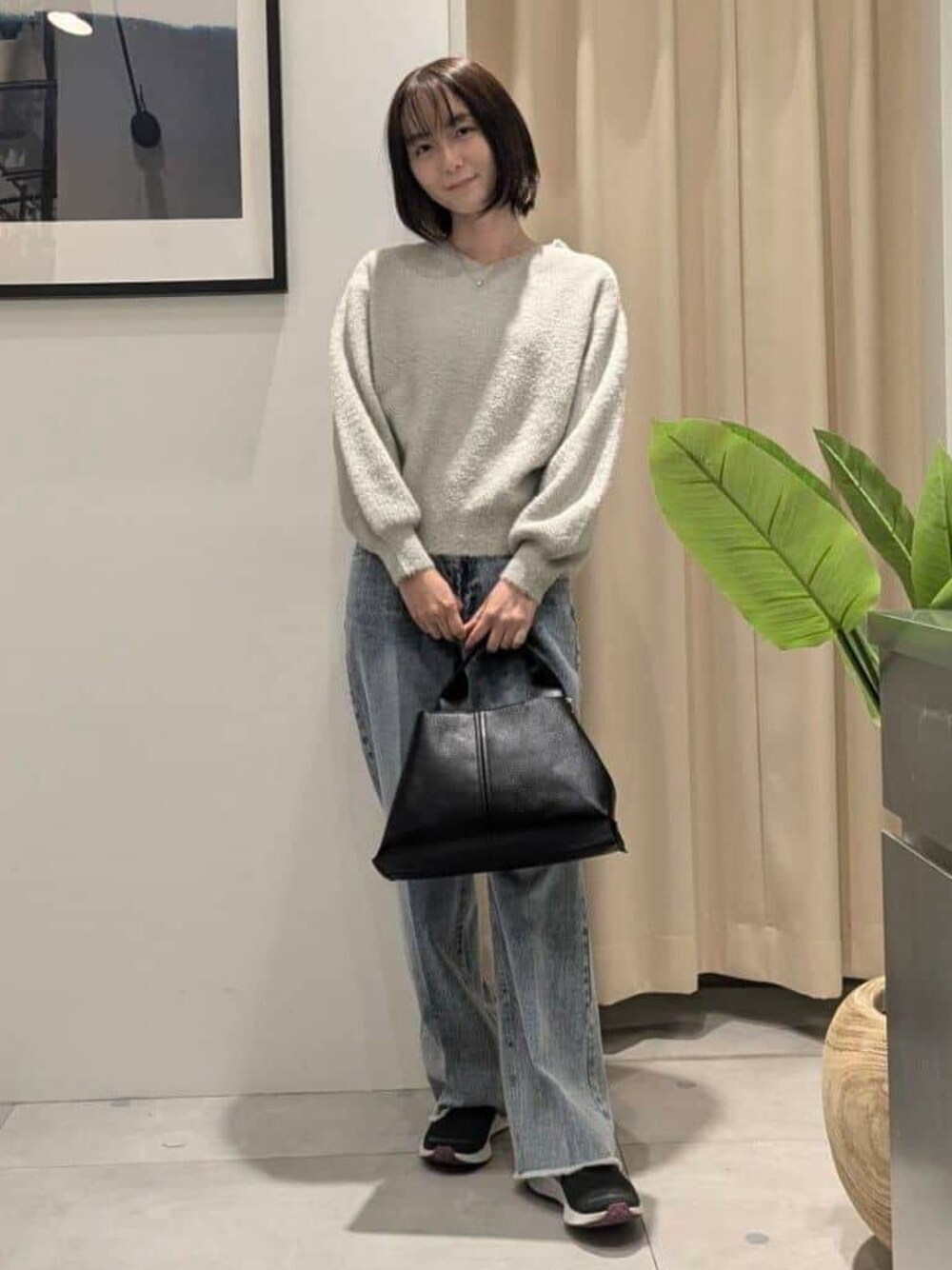 ベージュ系のニット/セーター、ブルー系のデニムパンツ、ブラック系のショルダーバッグを着用したレディースの秋コーディネートの1枚目の写真