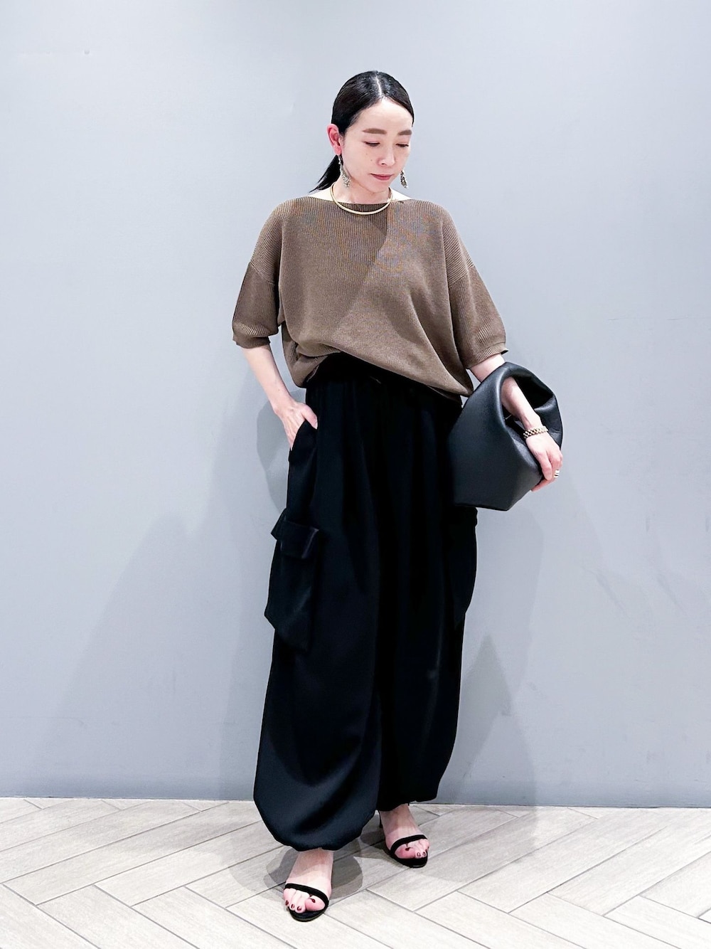 ブラック系のその他パンツ、ブラウン系のニット/セーター、ブラック系のハンドバッグを着用したレディースの春コーディネートの1枚目の写真