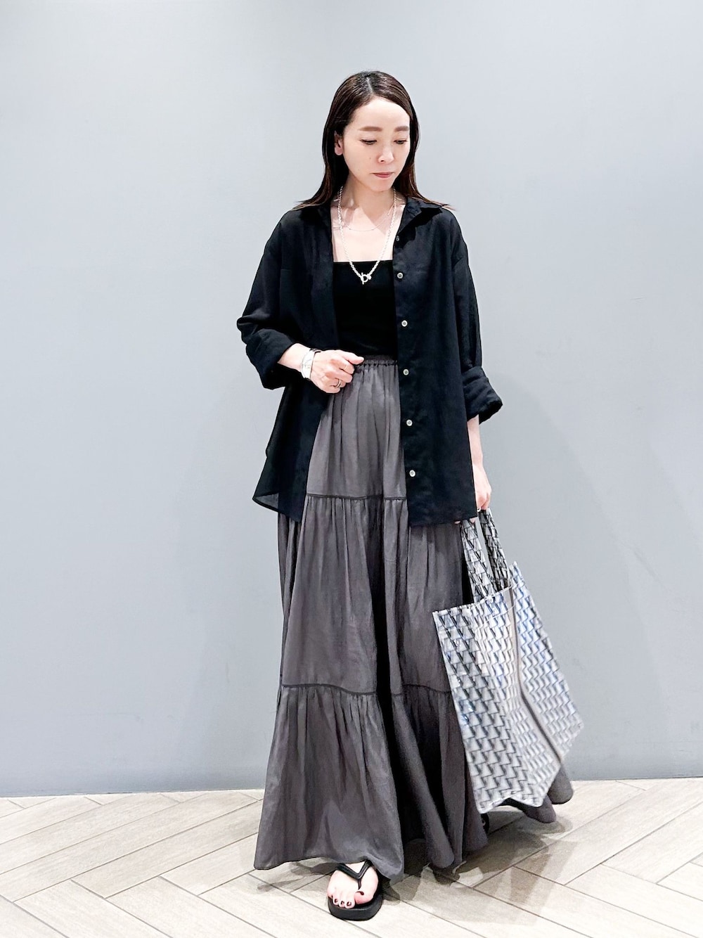 ブラック系のシャツ/ブラウス、グレー系のスカート、ブラック系のサンダルを着用したレディースの夏コーディネートの1枚目の写真