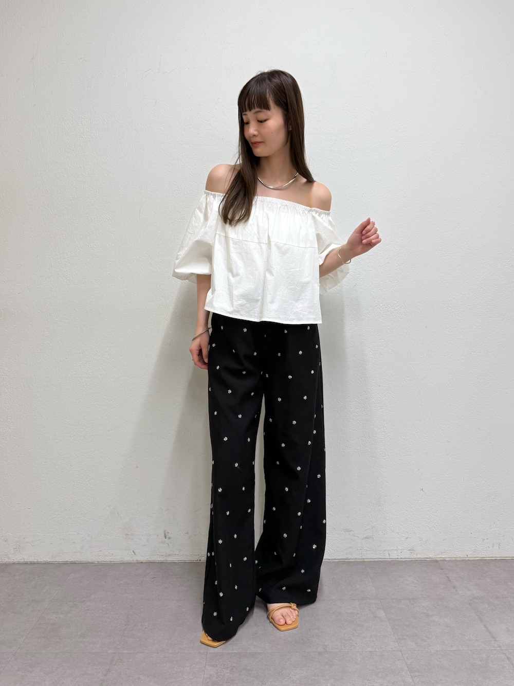 ホワイト系のシャツ/ブラウス、ブラック系のスラックス、ベージュ系のサンダルを着用したレディースの春コーディネートの1枚目の写真