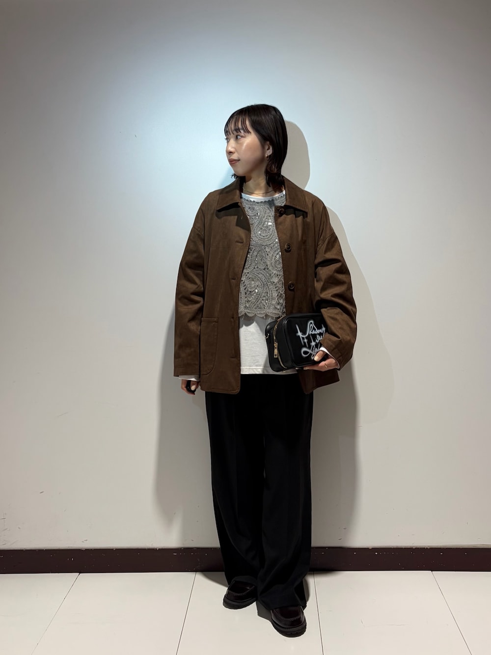 ブラック系のショルダーバッグ、ブラウン系のその他アウター、グレー系のTシャツ/カットソーを着用したレディースの春コーディネートの1枚目の写真