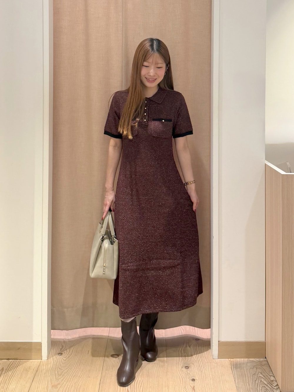 レッド系のワンピース、ベージュ系のトートバッグ、ブラウン系のブーツを着用したレディースの秋コーディネートの1枚目の写真