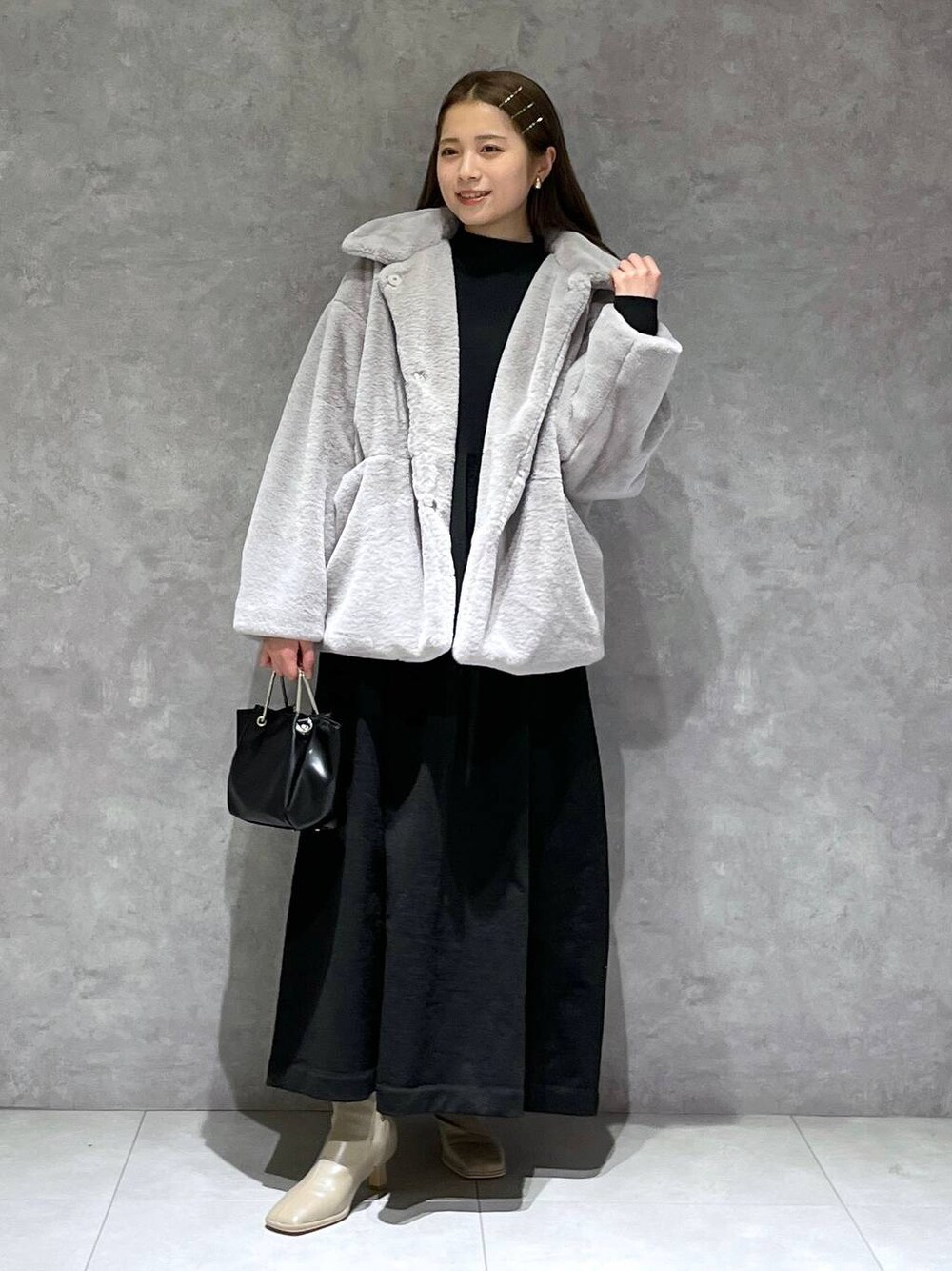 グレー系のその他アウター、ホワイト系のブーツ、ブラック系のワンピースを着用したレディースの冬コーディネートの1枚目の写真