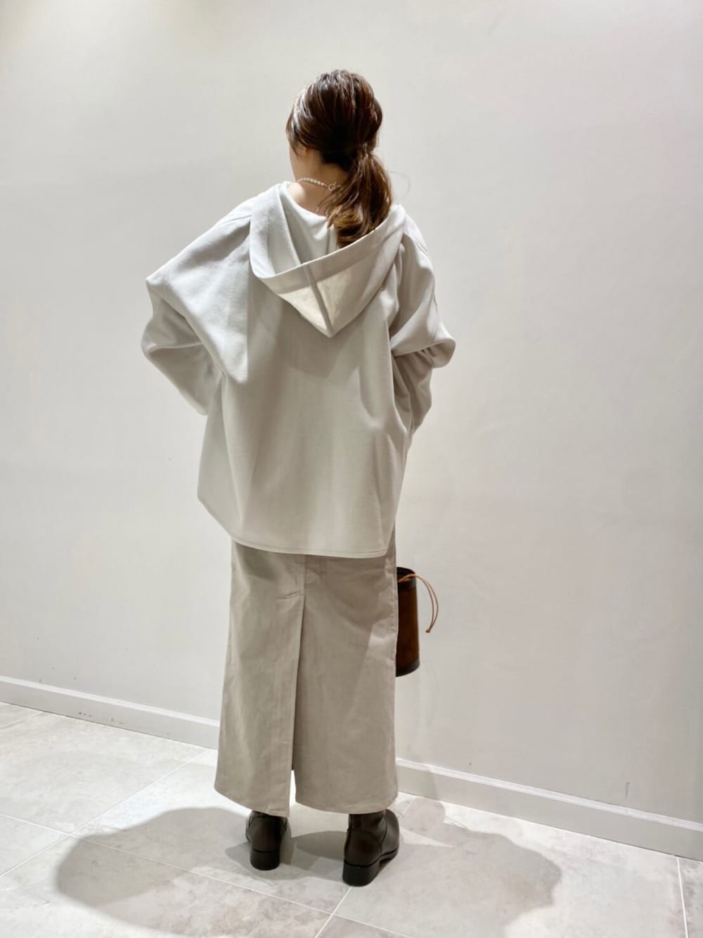 ブラック系のブーツ、ベージュ系のスカート、ホワイト系のシャツ/ブラウスを着用したレディースの秋コーディネートの1枚目の写真