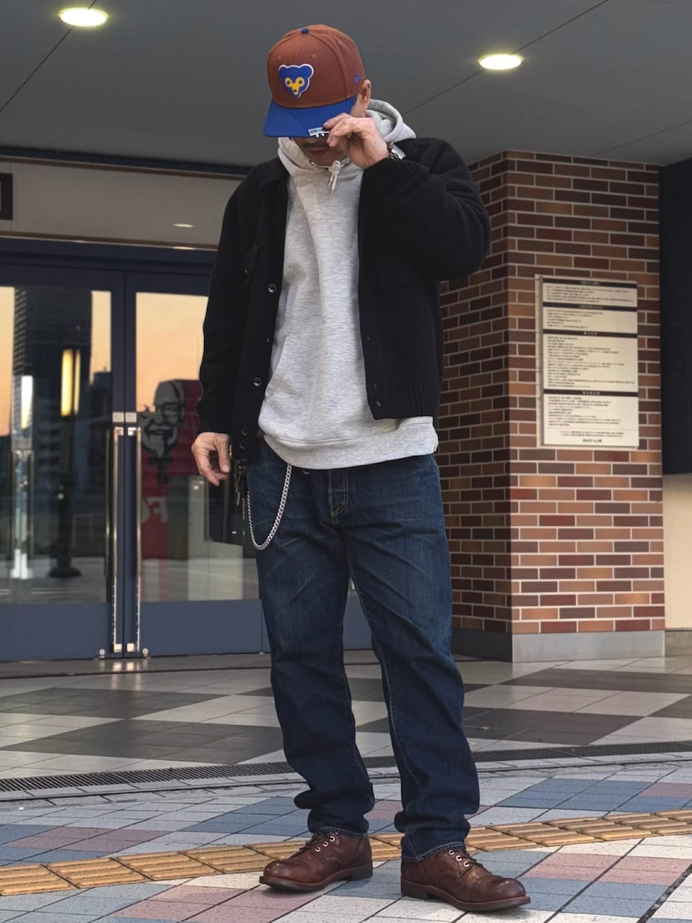 ブラック系のニット/セーター、グレー系のパーカー、ブルー系のデニムパンツを着用したメンズの春コーディネートの1枚目の写真
