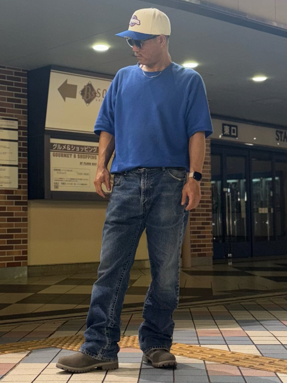 グレー系のブーツ、ブルー系のデニムパンツ、ブルー系のスウェットを着用したメンズの夏コーディネートの1枚目の写真