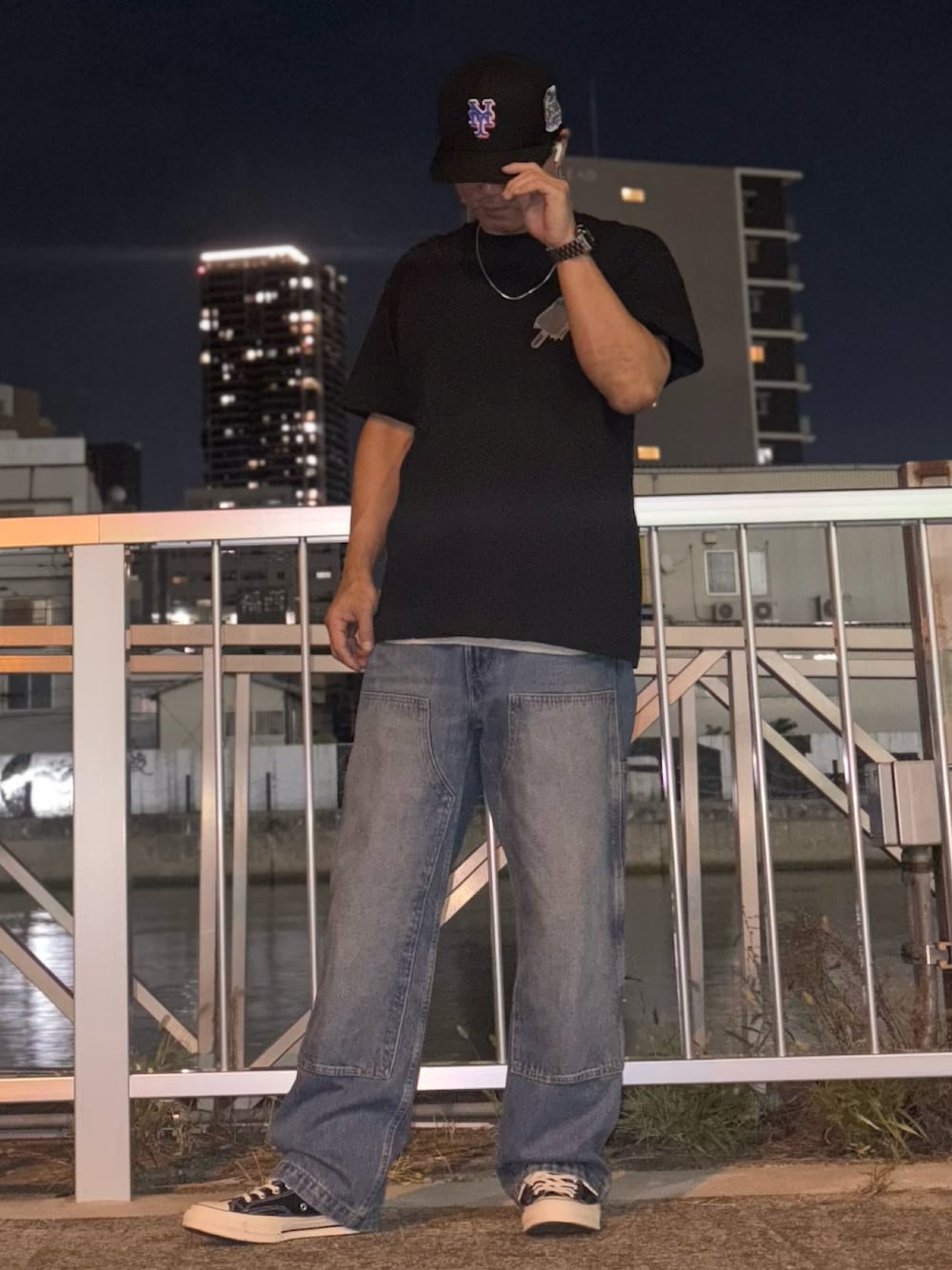 ブルー系のデニムパンツ、ブラック系のTシャツ/カットソー、ブラック系のスニーカーを着用したメンズの秋コーディネートの1枚目の写真