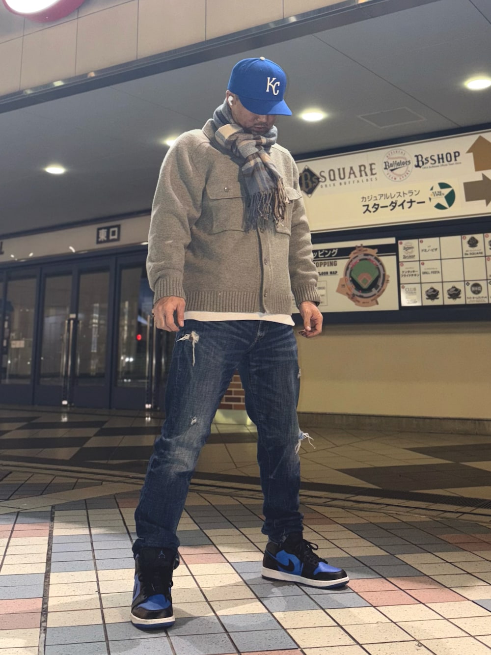 グレー系のニット/セーター、ブルー系のデニムパンツ、ブルー系のスニーカーを着用したメンズの冬コーディネートの1枚目の写真