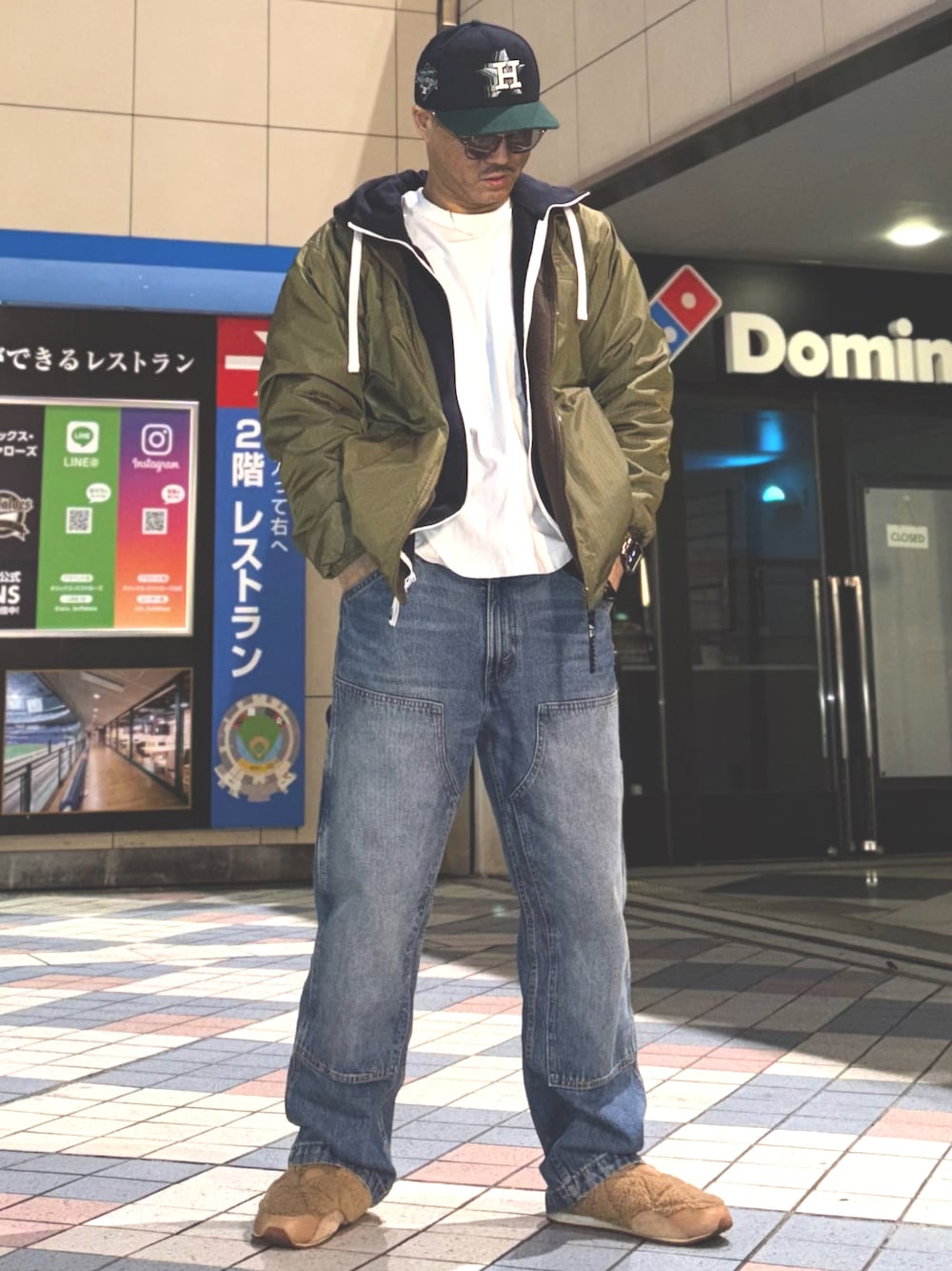 グリーン系のナイロンジャケット、ブルー系のパーカー、ホワイト系のTシャツ/カットソーを着用したメンズの春コーディネートの1枚目の写真