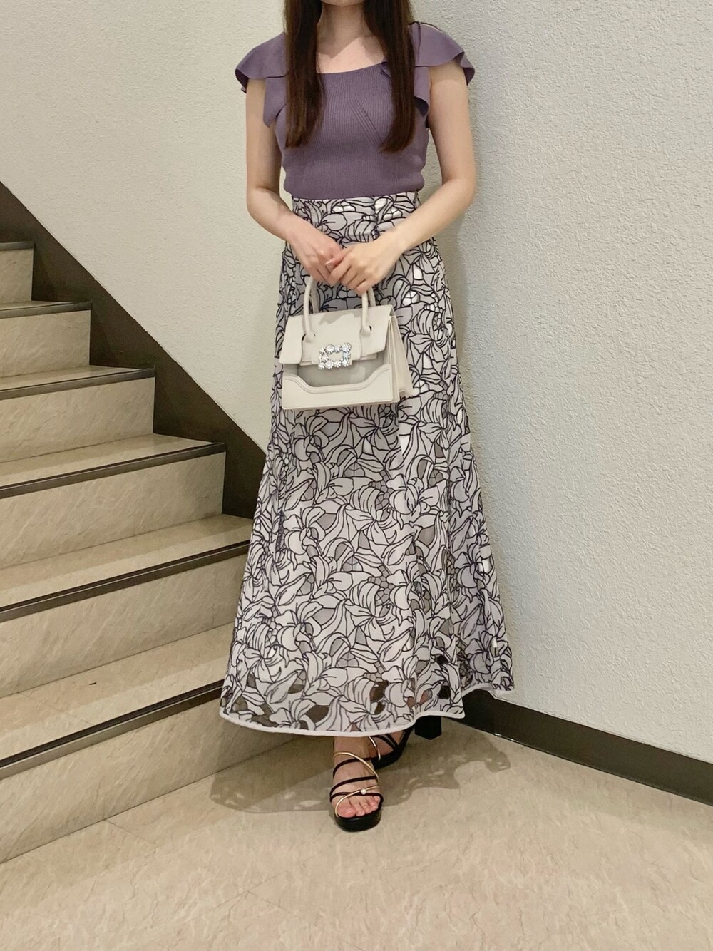 パープル系のニット/セーター、ベージュ系のショルダーバッグ、ベージュ系のスカートを着用したレディースの春コーディネートの1枚目の写真