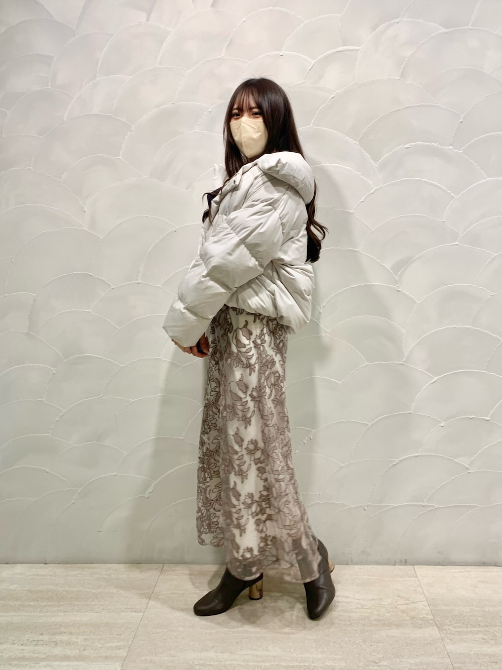 ピンク系のスカート、グレー系のニット/セーター、ホワイト系のダウンジャケット/コートを着用したレディースの秋コーディネートの1枚目の写真