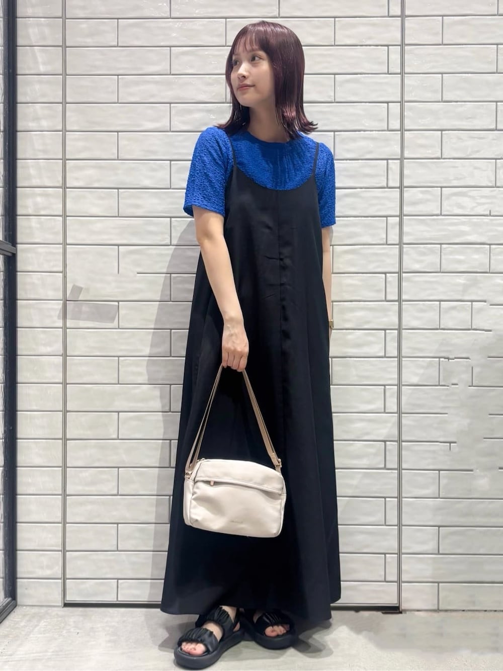 ブルー系のTシャツ/カットソー、ブラック系のワンピース、ベージュ系のショルダーバッグを着用したレディースの夏コーディネートの1枚目の写真