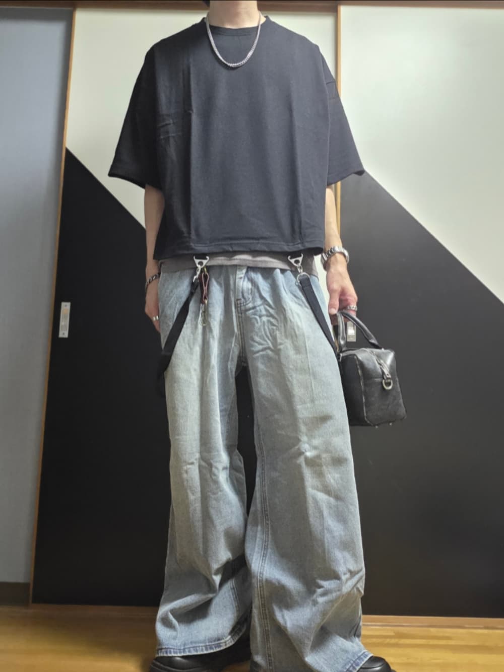 ブルー系のデニムパンツ、ブラック系のショルダーバッグ、ブラック系のタンクトップを着用したメンズの夏コーディネートの1枚目の写真