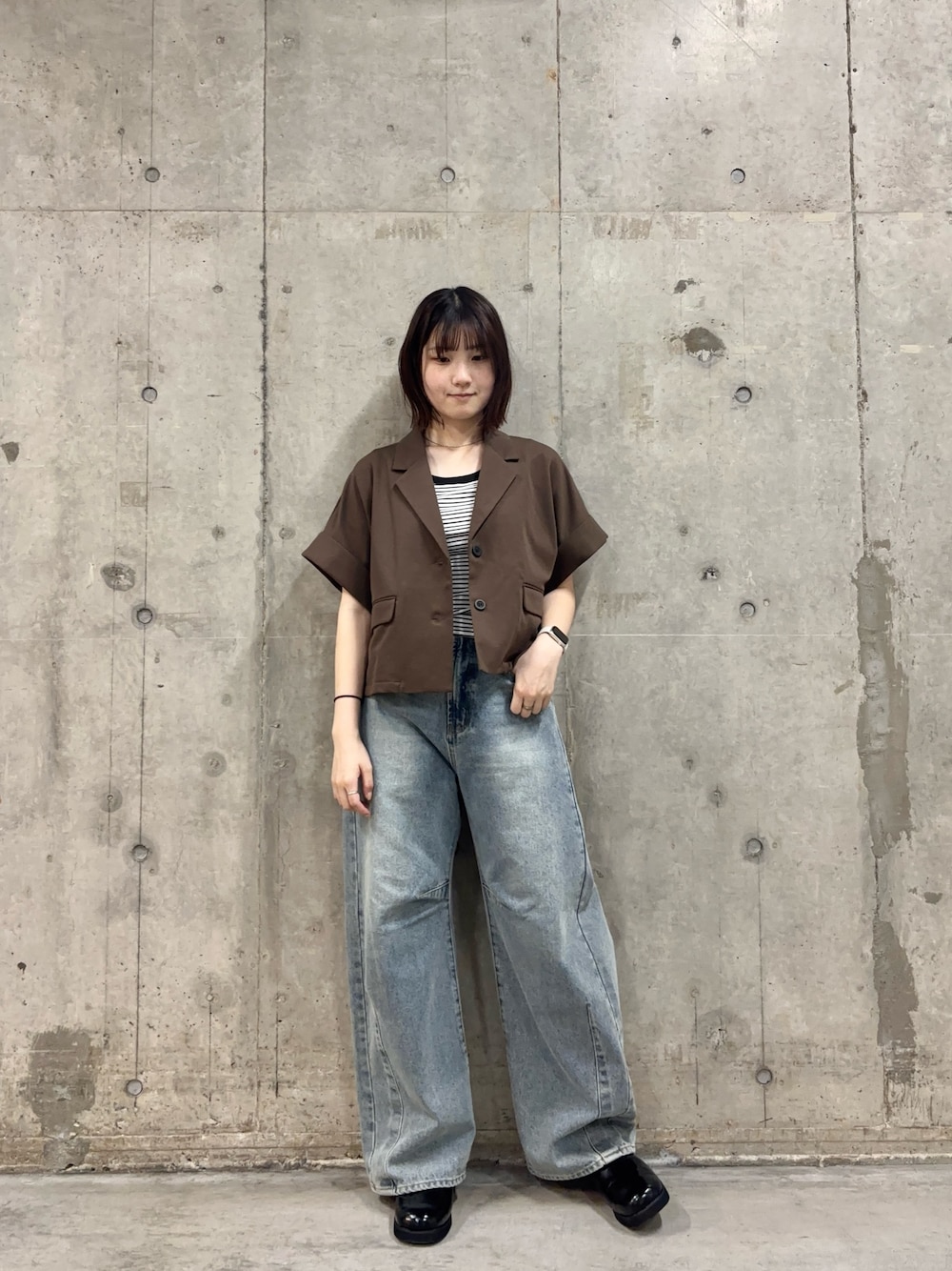 ブラウン系のその他アウター、ホワイト系のTシャツ/カットソー、ブラック系のサンダルを着用したレディースの春コーディネートの1枚目の写真