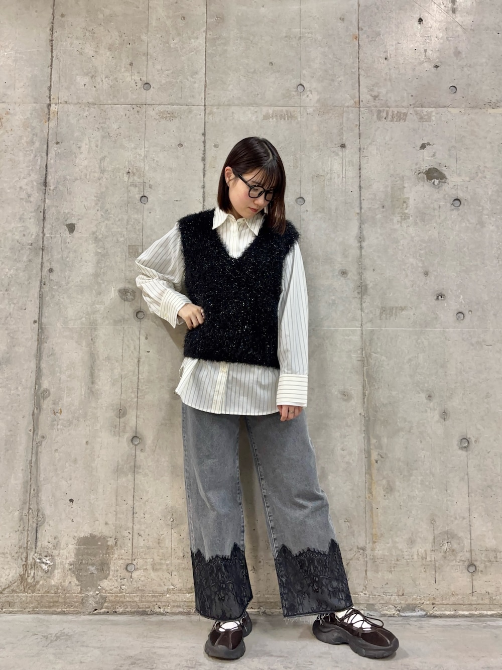 ブラック系のベスト、ブラウン系のスニーカー、グレー系のデニムパンツを着用したレディースの冬コーディネートの1枚目の写真