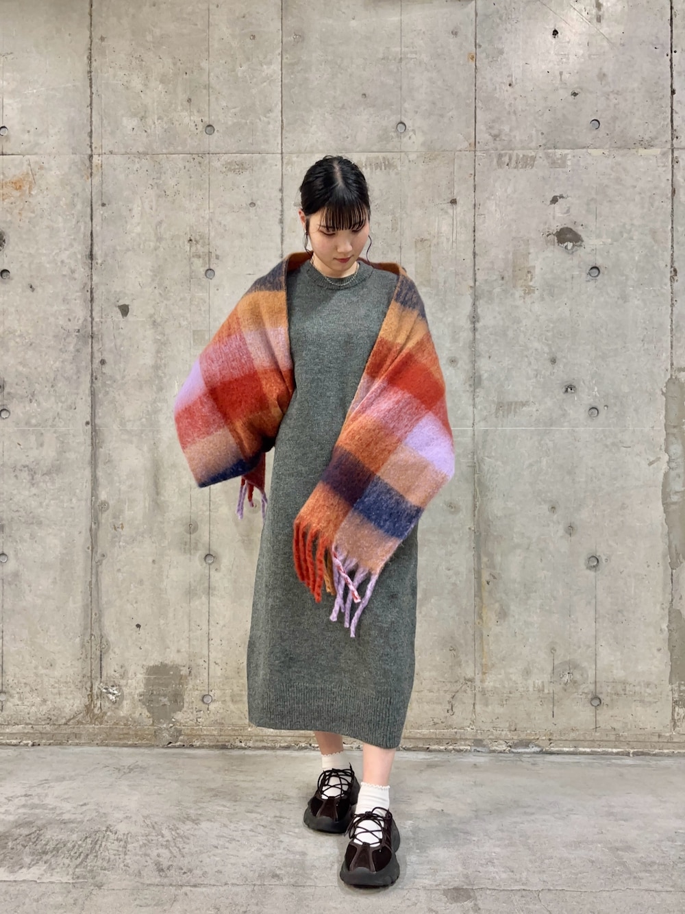 グレー系のワンピース、ブラウン系のスニーカー、オレンジ系のマフラーを着用したレディースの秋コーディネートの1枚目の写真