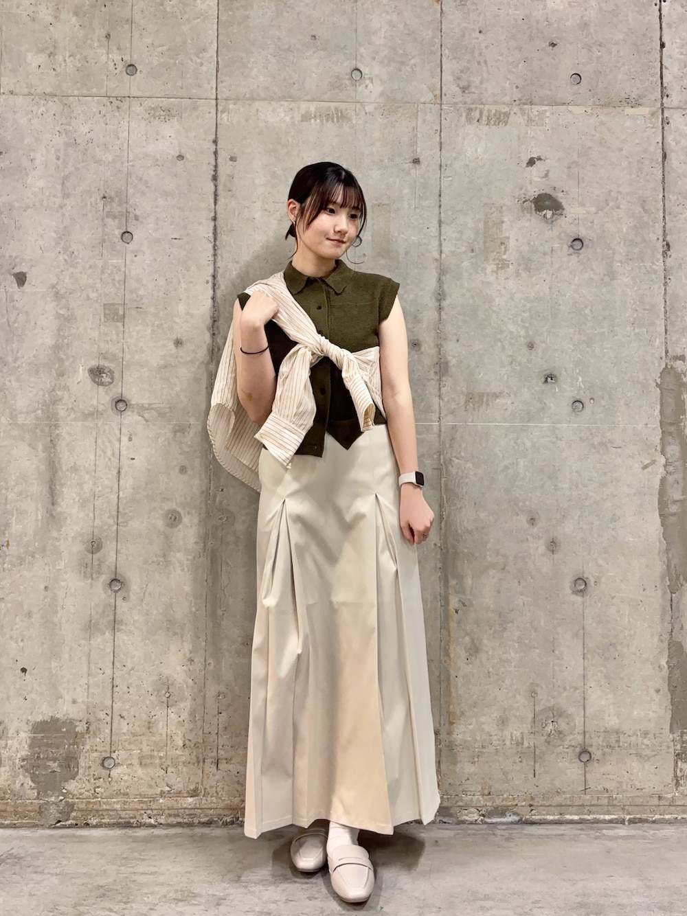 グリーン系のニット/セーター、ベージュ系のシャツ/ブラウス、ホワイト系のスカートを着用したレディースの春コーディネートの1枚目の写真