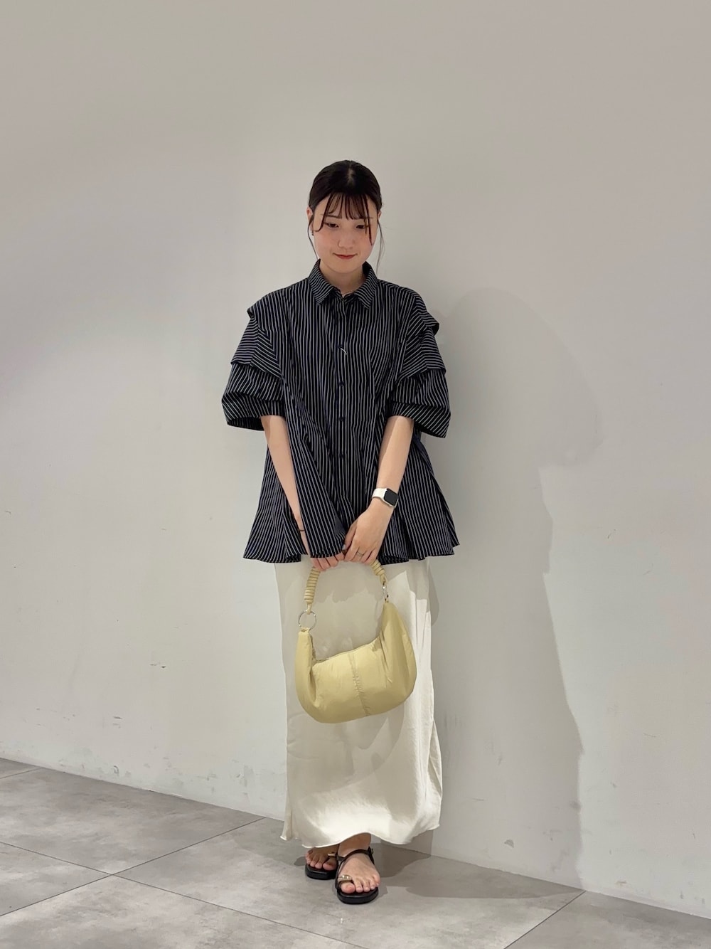 ホワイト系のスカート、ブルー系のシャツ/ブラウス、ベージュ系のハンドバッグを着用したレディースの夏コーディネートの1枚目の写真