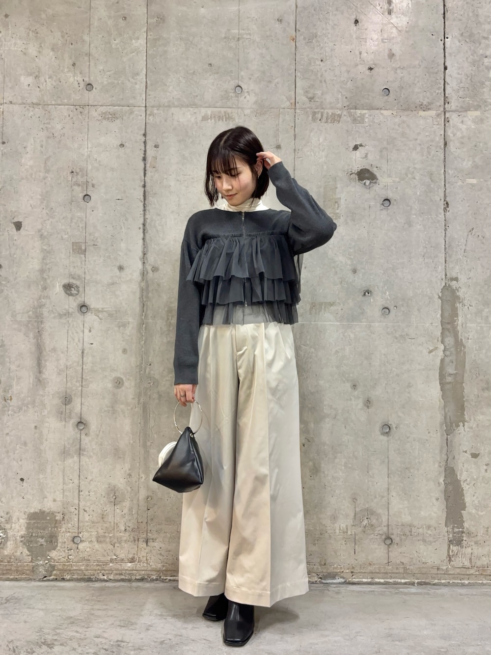 ホワイト系のチノパンツ、ブラック系のハンドバッグ、ブラック系のブーツを着用したレディースの冬コーディネートの1枚目の写真